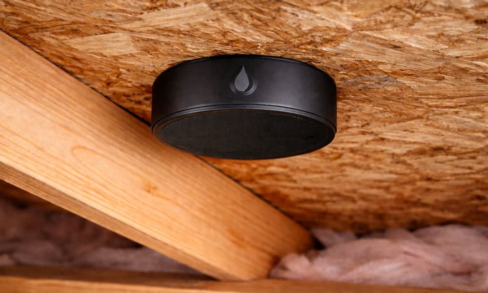 Wireless moisture sensor installed on attic ceiling to monitor roof and insulation moisture levels