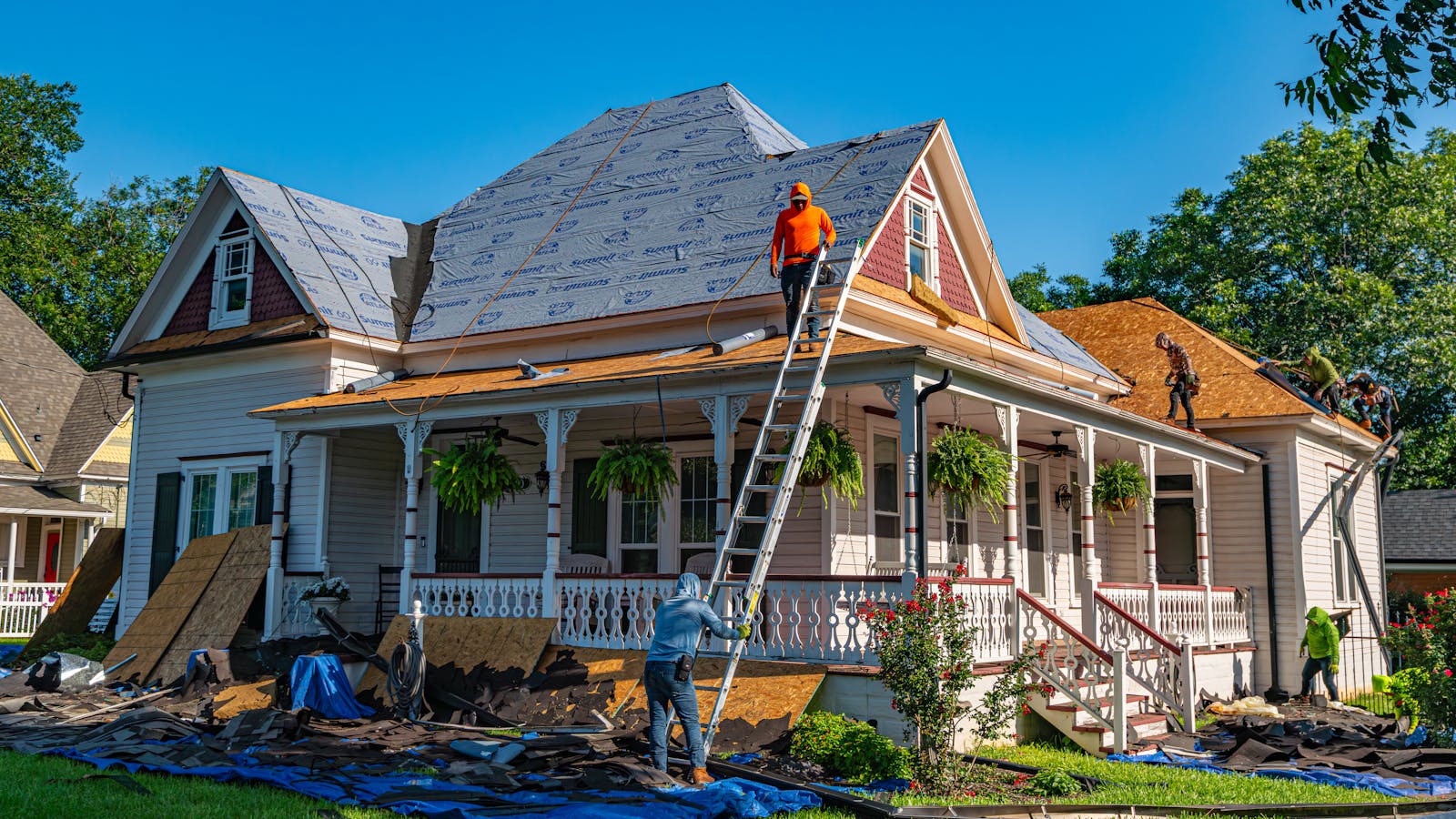 Roofers replacing the roof of a historic home, illustrating full roof replacement.