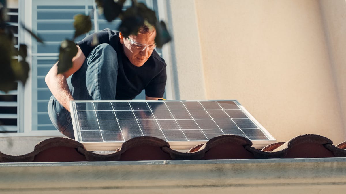 A technician installing a solar panel on a house roof, highlighting the installation process of solar shingles and solar roofing solutions.