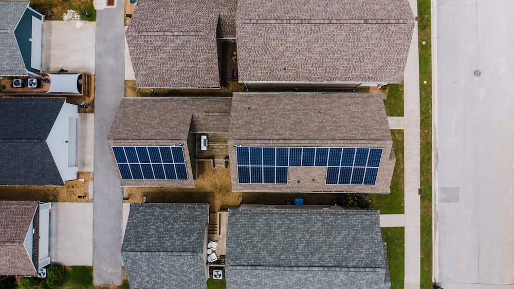 Aerial view of suburban houses featuring solar panels on roofs, representing solar shingles and rooftop solar energy in a residential area.