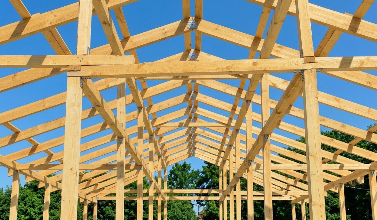 A low-angle shot of a wooden building frame and roof trusses under construction