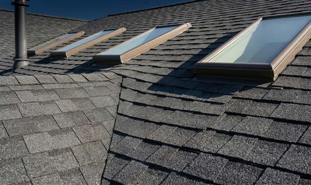A close-up, horizontal orientation view of a dark grey asphalt shingle roof