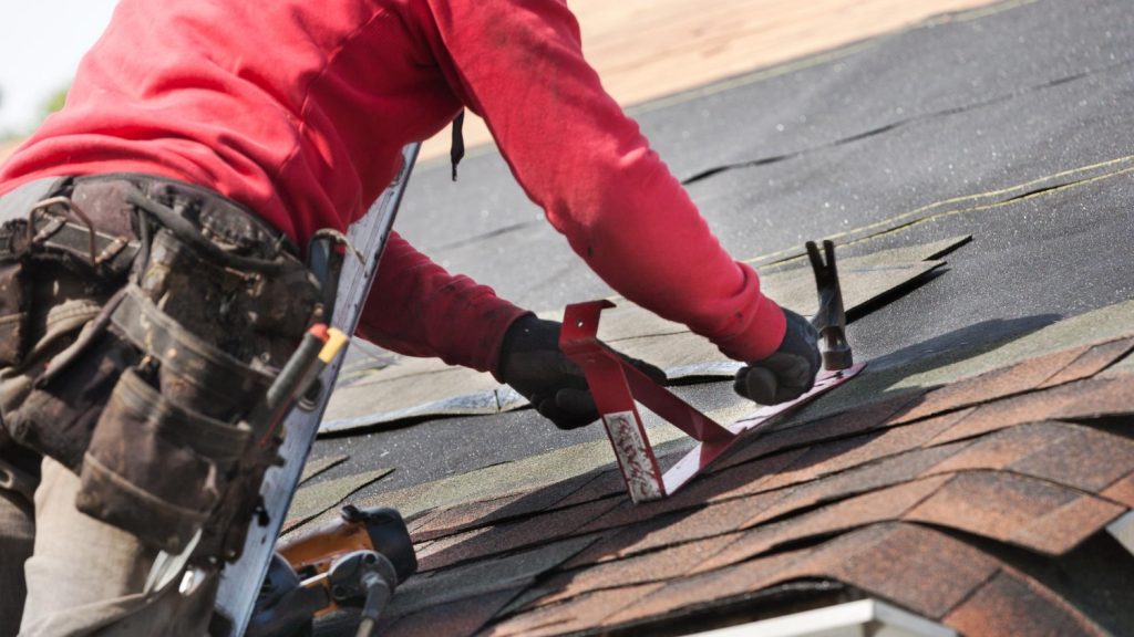 Roofer installing shingles on a residential roof