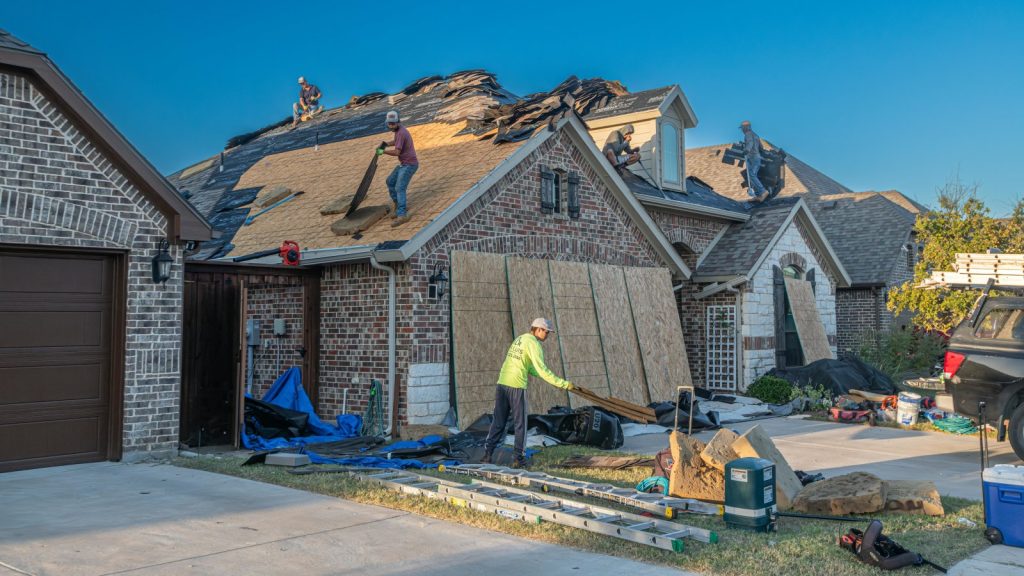 Workers engaged in roof replacement on a brick house