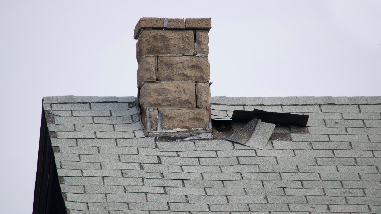 an asphalt shingle roof with visible storm damage