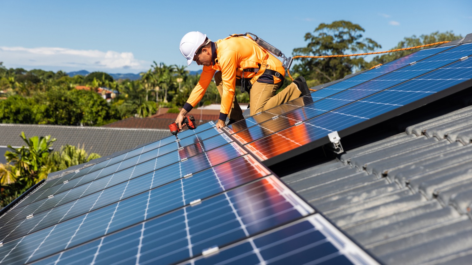installing blue solar panels onto a residential tiled roof