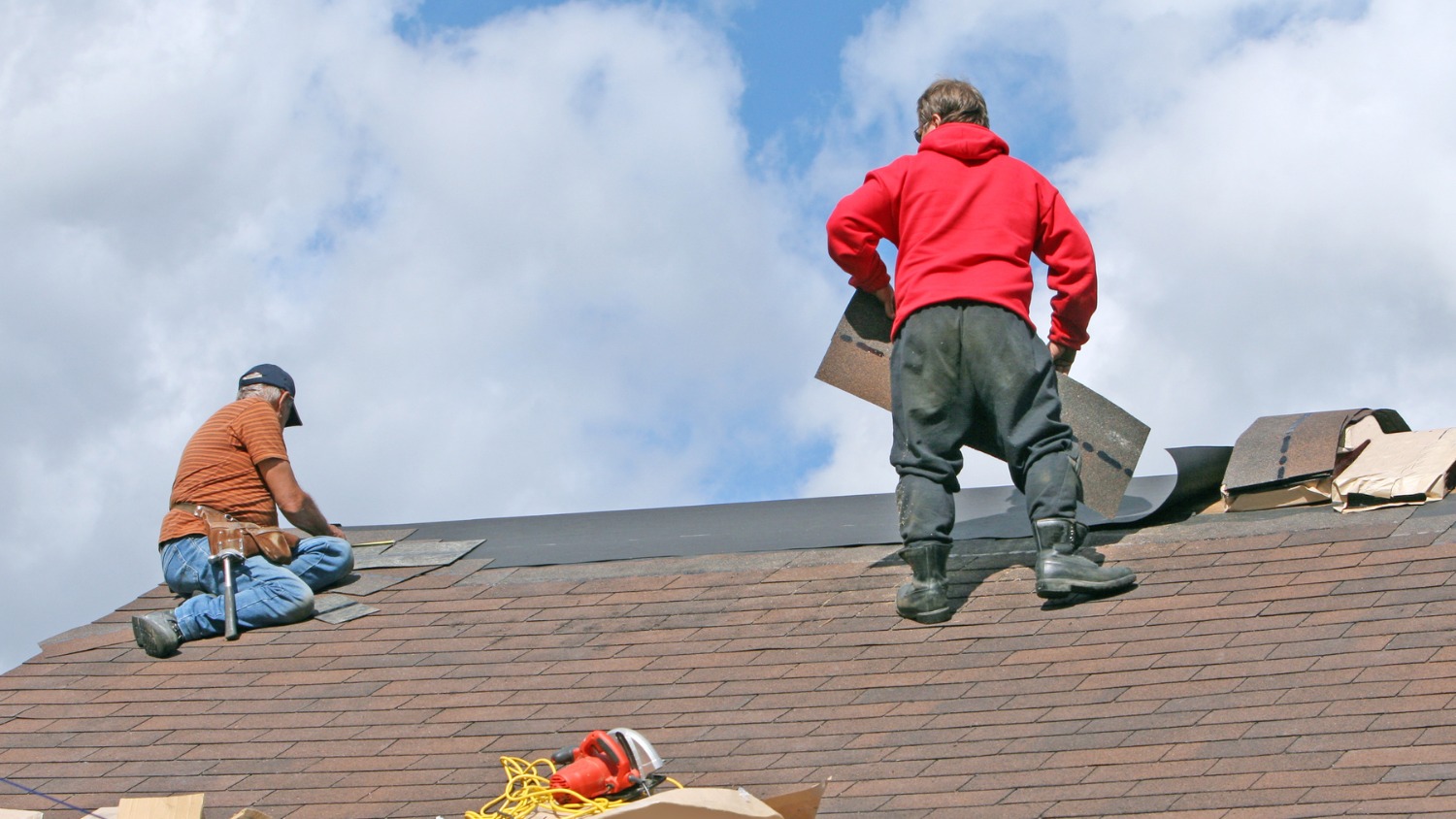 Two roofers installing new asphalt shingles