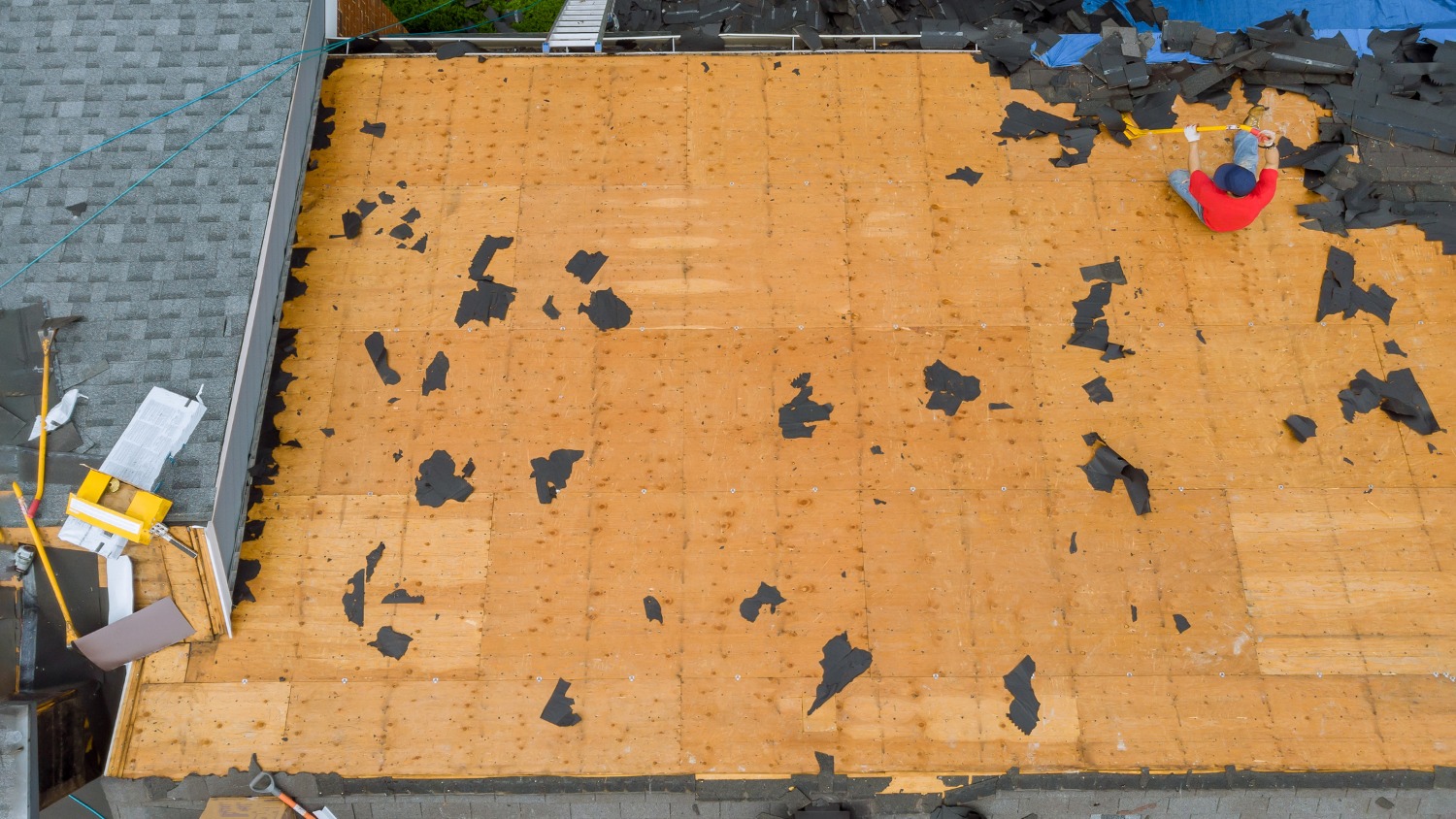 High-angle view of a worker stripping asphalt shingles