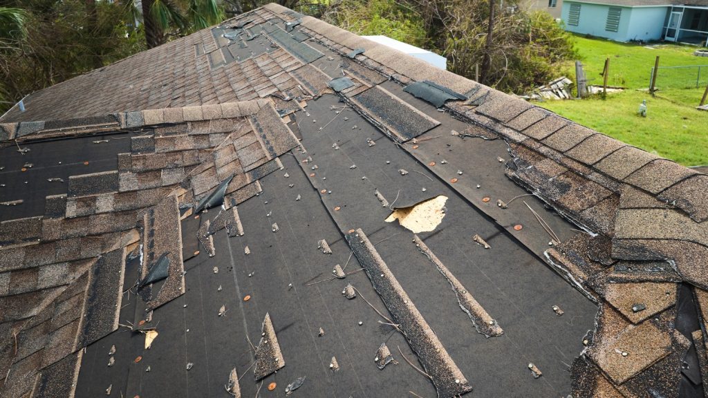 aerial view of a residential shingle roof with severe storm damage