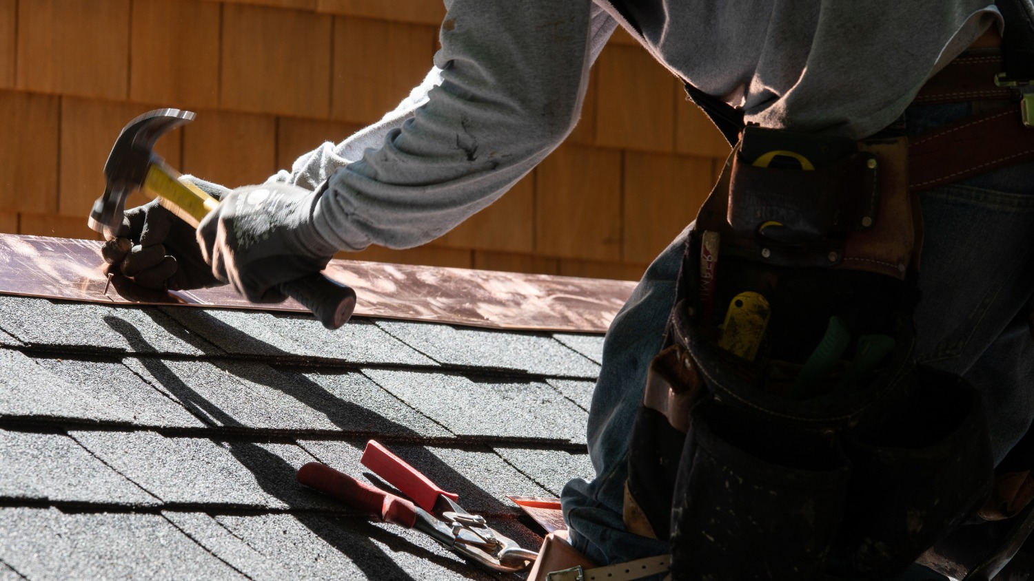 Roofer hammering flashing on a shingled roof