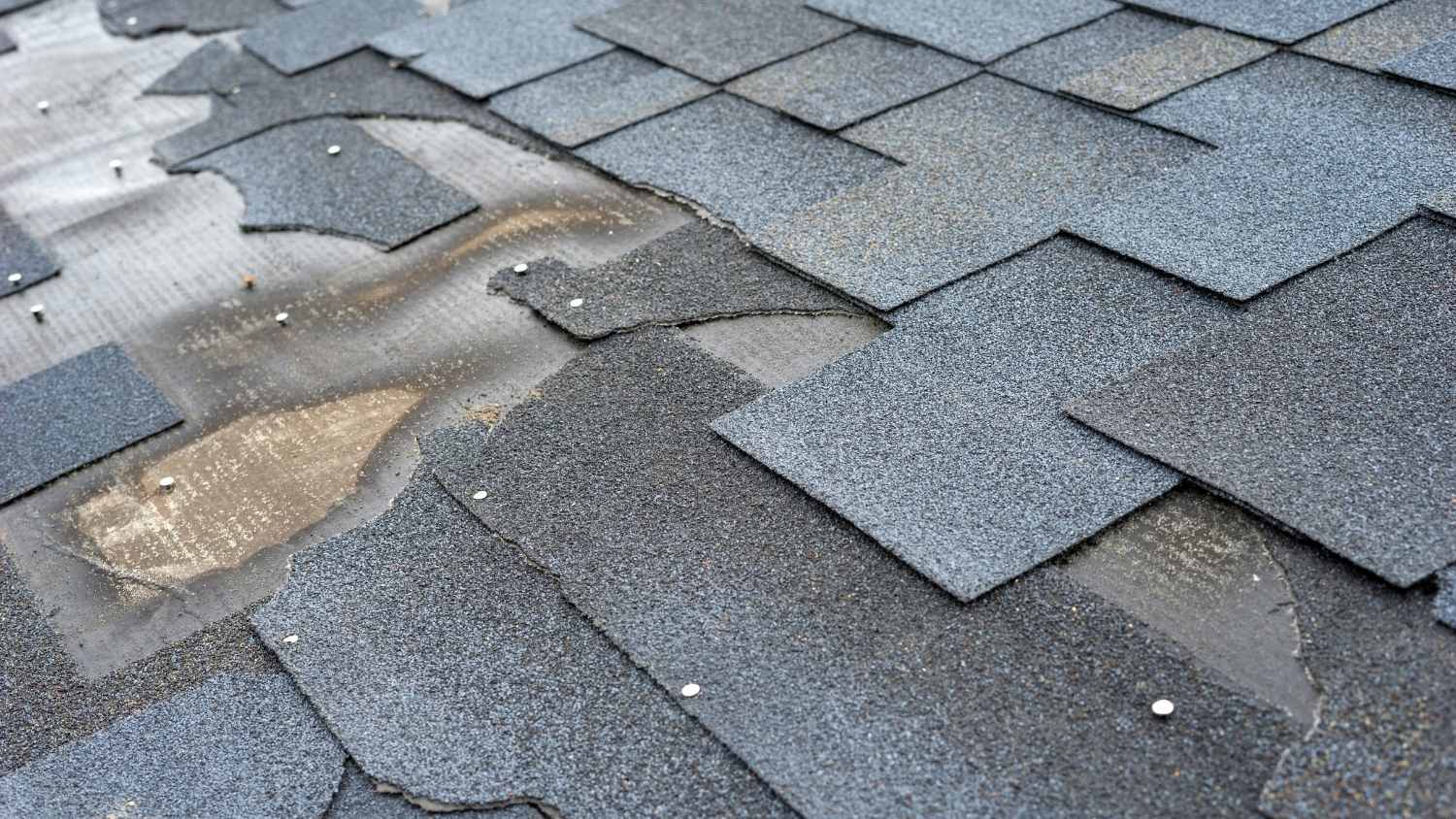damaged roof showing torn, broken, and missing grey asphalt
