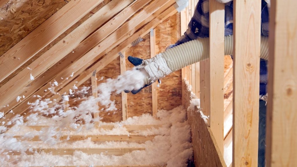 insulation blower hose being used to spray loose-fill insulation