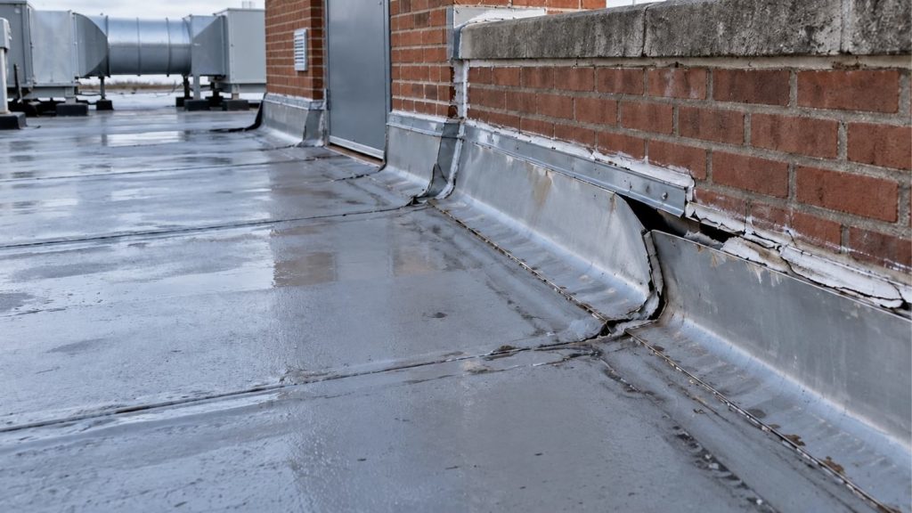 lifted metal flashing, cracked sealant, and a separated flashing lap along one section