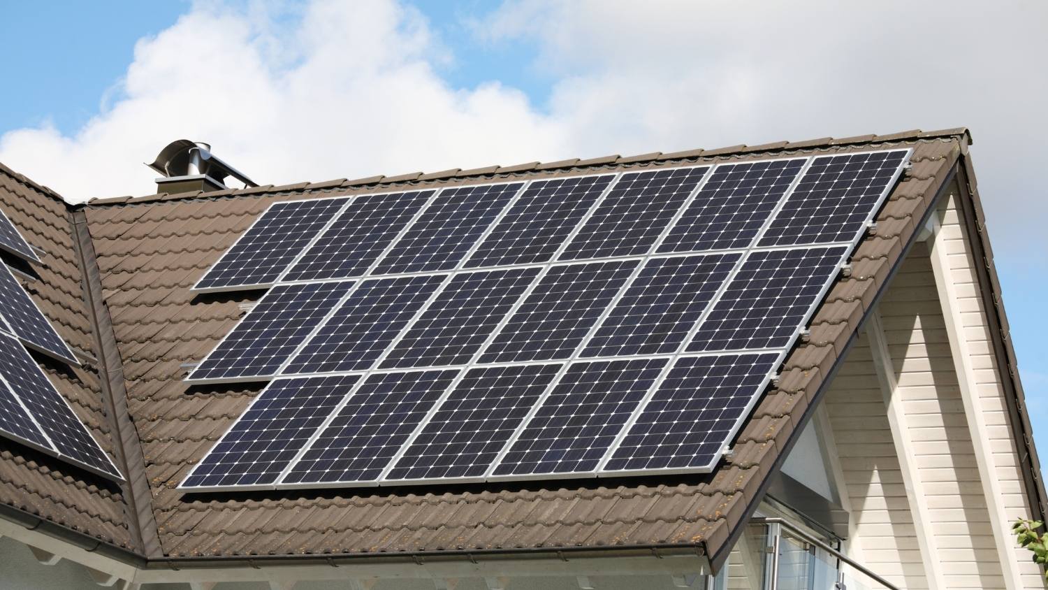 dark brown tiled residential roof arrayed with a grid of twenty monochromatic solar panels