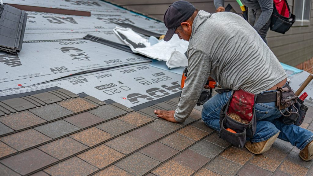 Skilled roofing contractor installing asphalt shingles on residential roof.